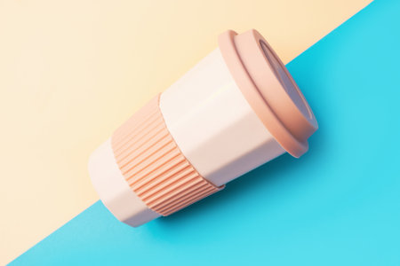 Reusable ceramic cup for coffee with silicone lid on a blue and yellow background.の写真素材