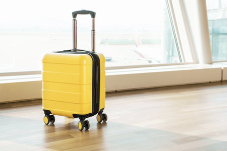 Yellow luggage bag on wheels at the airport, side view.の写真素材