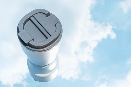White mug against the background of a blue sky with clouds close-up.