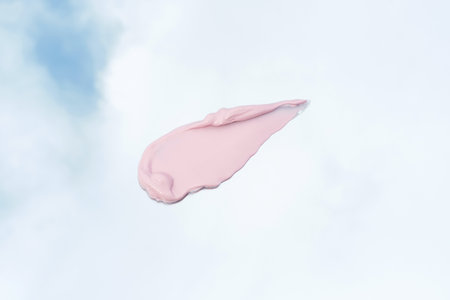 Pink cosmetic clay smear against the background of sky with clouds close up.の写真素材