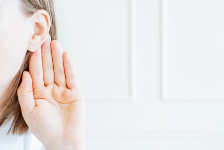 Female hand holding ear on white background close-up.