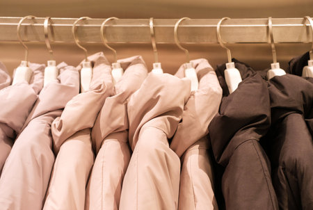 Winter down jackets hanging on a wooden hangers in clothing store, side view.の写真素材