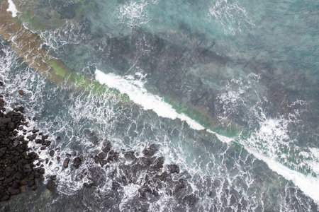 Sea and volcanic rocks close-up aerial view, natural background.