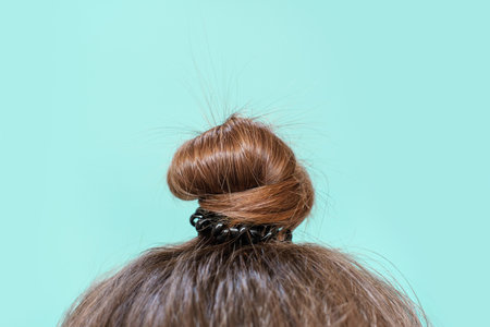 Modern hairstyle bun on a blue background, copy space.の写真素材
