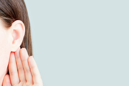 The woman listens attentively with her palm to her ear close-up isolated on gray background, news concept.の写真素材