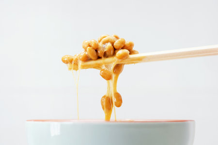 Wooden chopsticks holding japanese natto beans on gray background.の写真素材