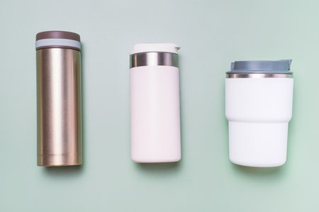 Two thermo mug and thermos on a green background, top view close-up.の写真素材