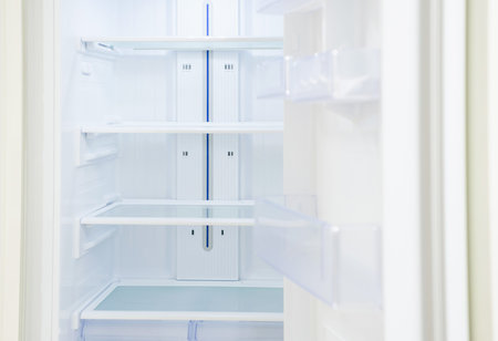 Modern white open refrigerator close up with empty shelves, front view.の写真素材