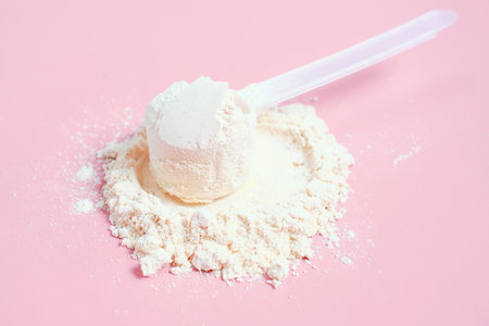 Protein powder in scoop on pink background, side view.の写真素材