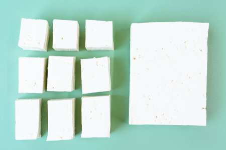 Whole tofu and sliced on green background, top view.の写真素材