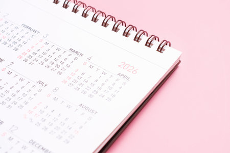 Paper calendar for 2026 on pink background close-up.