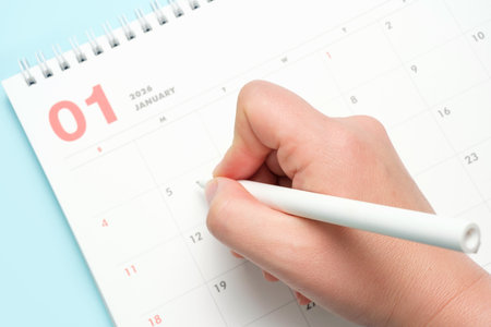 Female hand and calendar january 2026 on blue background top view.の写真素材
