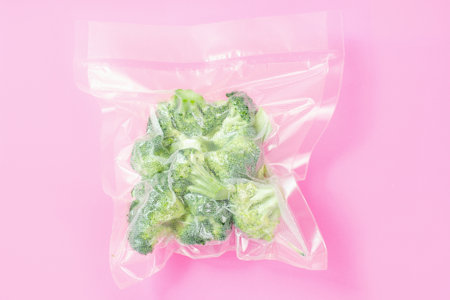 Vacuum bag with broccoli on pink background close-up.の写真素材