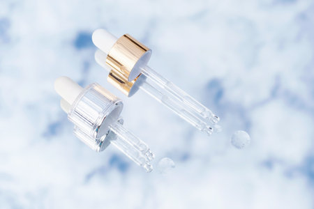 Two pipettes with serum on the background of blue sky and clouds, skin care concept.の写真素材