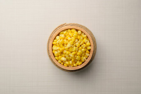 Bowl with corn seeds in bowl and ripe corn cobs top on wooden tableの写真素材