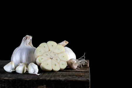 Close up garlic on wooden table, isolated on a black backgroundの写真素材