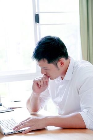 A Portrait of young asian man working with laptop  and showing gesture signの写真素材
