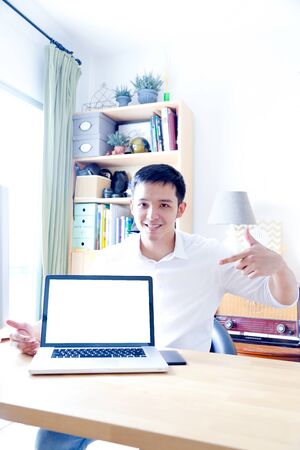 A Portrait of young asian man working with laptop  and showing gesture signの写真素材