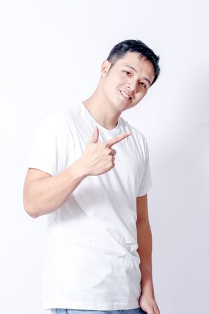 A Portrait of young asian man in white shirt and blue jeans  showing gesture sign or devicesの写真素材