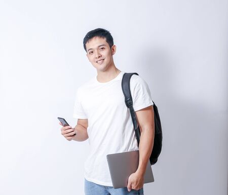 A Portrait of young asian man in white shirt and blue jeans  showing gesture sign or devicesの写真素材