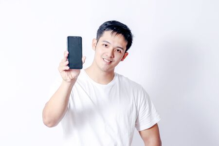 A Portrait of young asian man in white shirt and blue jeans  showing gesture sign or devicesの写真素材