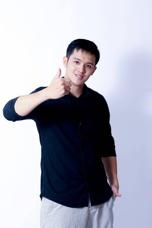 A Portrait of young asian man wearing Black Shirt showing gesture sign or devicesの写真素材