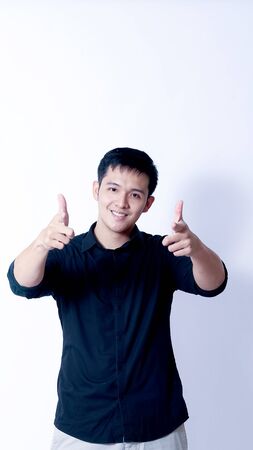 A Portrait of young asian man wearing Black Shirt showing gesture sign or devicesの写真素材