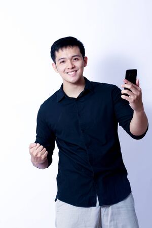 A Portrait of young asian man wearing Black Shirt showing gesture sign or devicesの写真素材