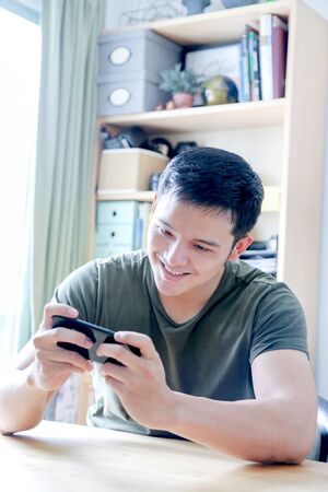 young asian wearing a green tshirt working with laptop in home officeの写真素材