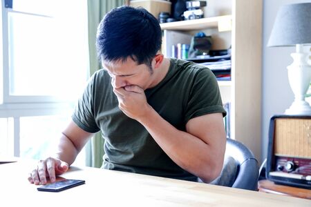 young asian wearing a green tshirt working with laptop in home officeの写真素材