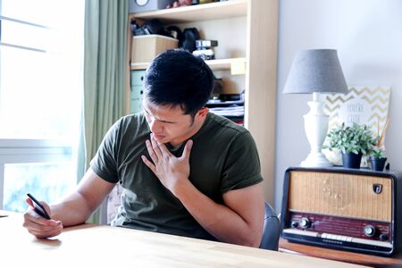 young asian wearing a green tshirt working with laptop in home officeの写真素材