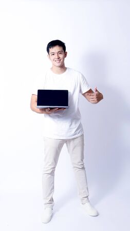 A Portrait of young asian wearing a Green t-shirt and white jeans showing gesture sign or devicesの写真素材