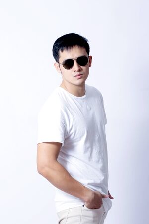 A Portrait of young asian wearing a Green t-shirt and white jeans showing gesture sign or devicesの写真素材