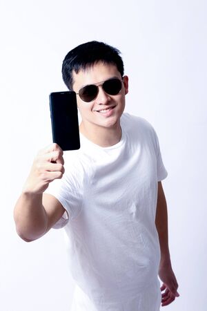 A Portrait of young asian wearing a Green t-shirt and white jeans showing gesture sign or devicesの写真素材
