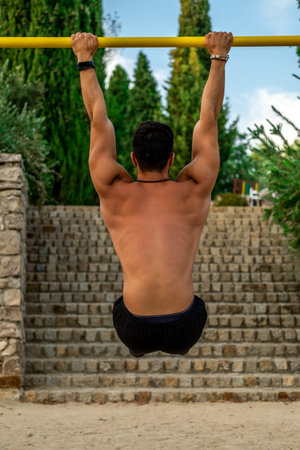 Close-up portrait from behind young Latino man without a shirt and black pants and mask training at...