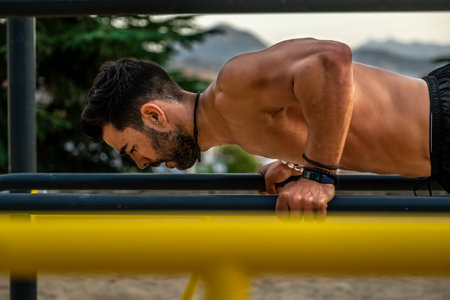 Close portrait of young Latin man without a shirt and black pants and mask training on the bar of a...