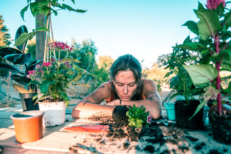Young sad latin woman wearing a red dress surrounded by plants and pots on a wooden table