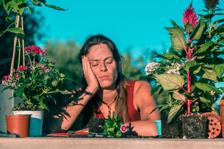 Young tired caucasian woman wearing a dress surrounded by plants and pots on a wooden table