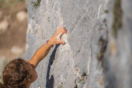 Close-up of a young woman's hand holding onto the stone while climbingの写真素材
