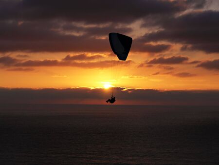 Hang glider over ocean sunsetの写真素材