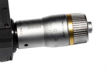 Detail view of the adjusting wheel of the micrometer screw on a white background