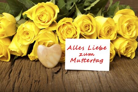 Yellow roses with stone heart and a card with the words  Alles Liebe zum Muttertag の写真素材