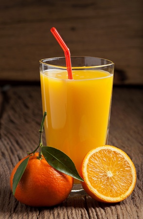 Freshly squeezed orange juice with a drinking straw on an old wooden tableの写真素材
