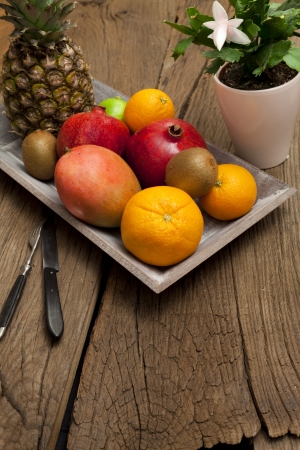Wooden bowl with fruits and a flower in a pot on an old wooden tableの写真素材