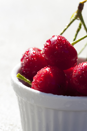 Some Cherries with shiny Water Drops in a white bowlの写真素材