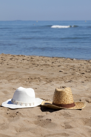 Two Straw Hats on the Beach with the Sea in the Background with Copy Space in upper part of imageの写真素材