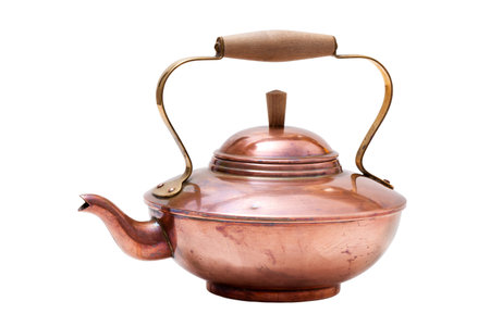 Old nostalgic copper tea pot with wooden handle isolated on white background