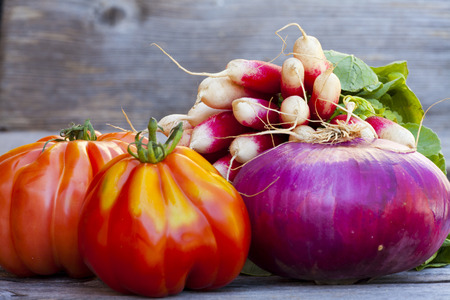 Coeur de Boeuf Tomatoes, large red Onions and Radishes fresh from the Weekly Market on a old wooden Tableの写真素材
