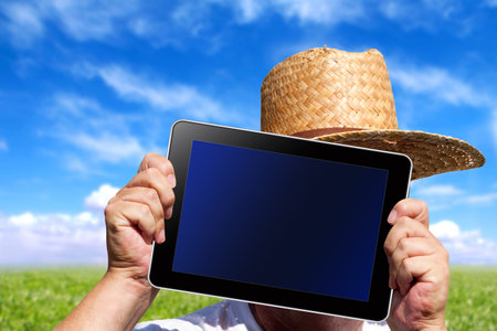 Human hands hold a digital Tablet with screen clipping path in front of green meadow and blue Skyの写真素材
