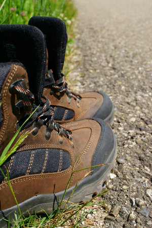 Close-up of Hiking boots on the roadside beside a summer meadowの写真素材